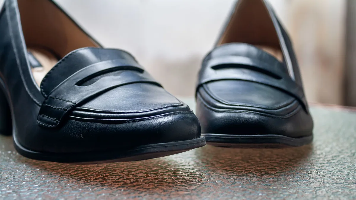 Close-up of stylish black leather women's shoes on a textured glass table.