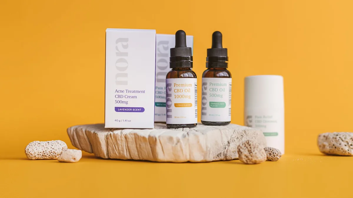 Close-up of CBD oil bottles and cream on a yellow background with natural textures.