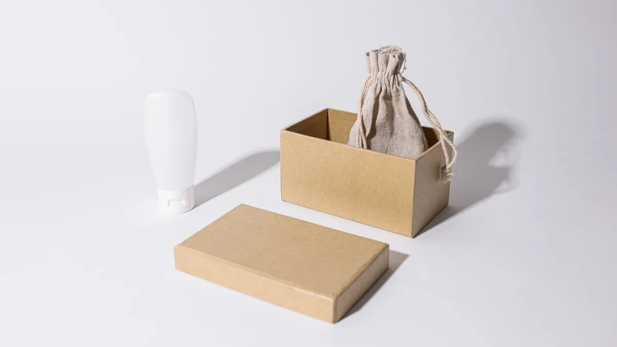 Stylish minimalist mockup featuring a cardboard box, linen pouch, and cream tube on a white background.